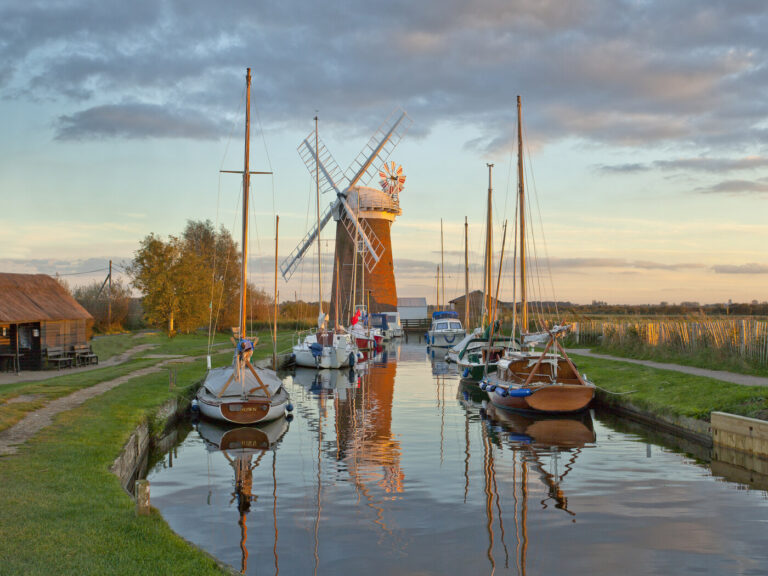 A landscape photo of a river scene with a windmill