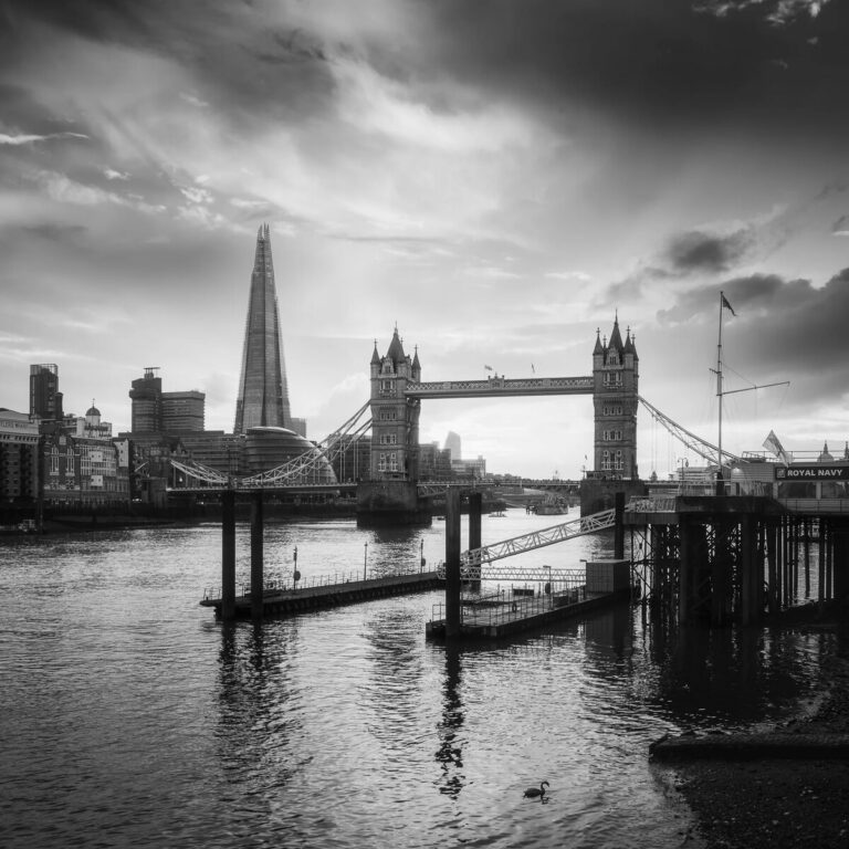 A black and white photo of a bridge over a river in a city